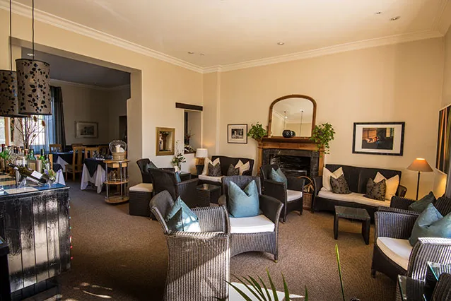 The lounge at Plantation House — deep sofas, a lit fireplace, Georgian proportions